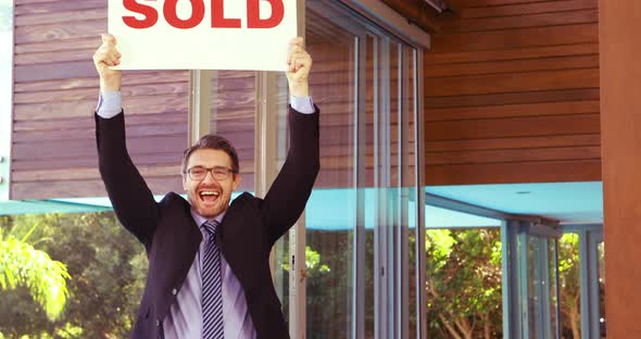 Estate agent cheering and holding SOLD sign