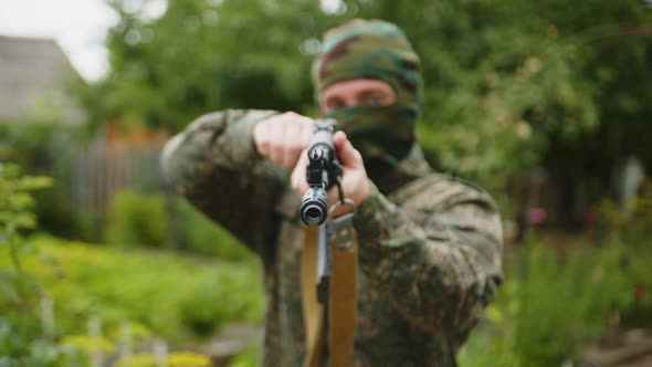 Closeup of a Masked Soldier Preparing to Fire and Pointing the Machine Gun Towards the Camera