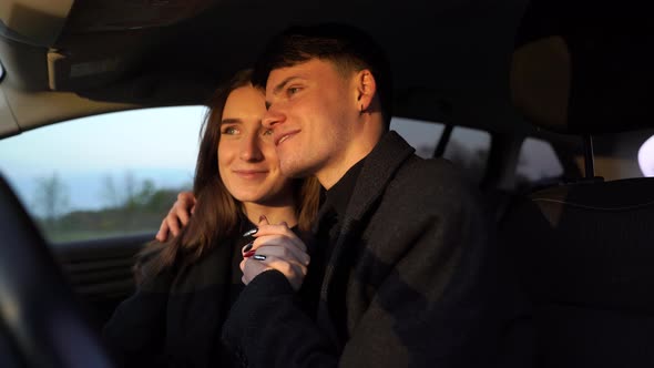 Romantic Couple Pretty Lovers Looking at Each Other with Tenderness and Sitting in Car at Sunset