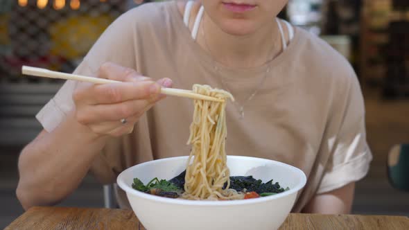 Hungry Girl Eating Noodles Out Her Ramen Soup with a Smile. Enjoying Healthy Organic Food