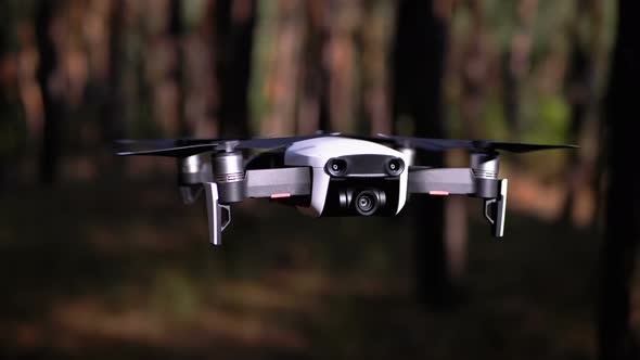 Drone with a Camera Hovers in the Air. Flies Above the Ground in the Forest. Slow Motion