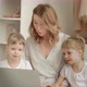 Mom with Twin Daughters Sitting at a Laptop and Looking Out the Window - VideoHive Item for Sale