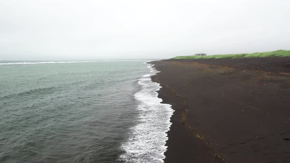 Black sand beach in Iceland with drone video low and moving forward.