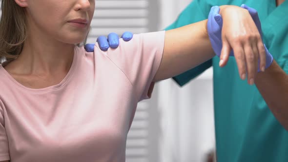 Rehabilitologist Moving Female Patient Hand, Treatment After Trauma or Surgery