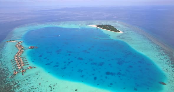 Aerial drone view of scenic tropical island and resort hotel with overwater bungalows in Maldives.