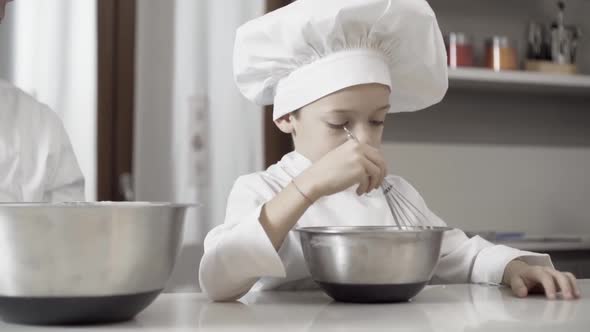 Closeup of a Boy Mixing Food Ingredients in Steel Bowl in Their Home Kitchen