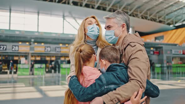 Happy Family of Four Embracing Together at Airport Building Enjoying Travel Vacation Everyone