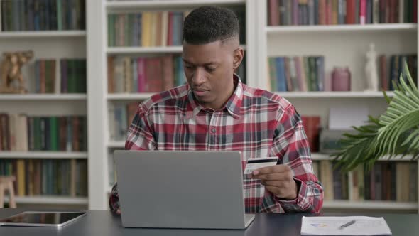 African Man making Online Payment Failure on Laptop in Office