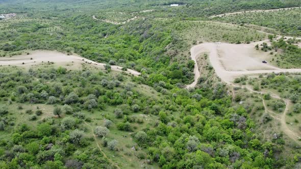 Drone footage of landscape and coutry roads with moving car and reveal of mountains