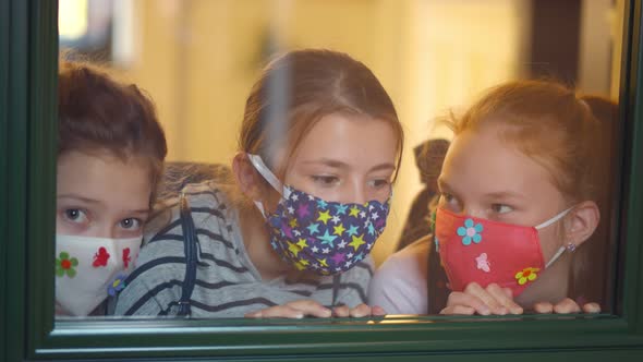 Children with Face Mask Looking Through Window in Classroom During Quarantine