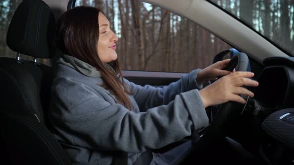 Woman Listens to Music and Dances in Car Parked Near Forest