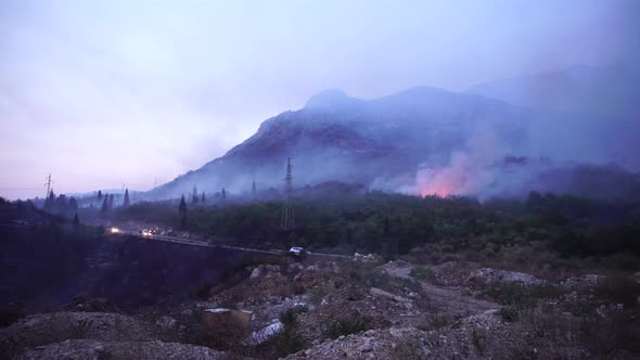 Cars with Headlights on Drives on the Highway Through the Smoke From a Forest Fire