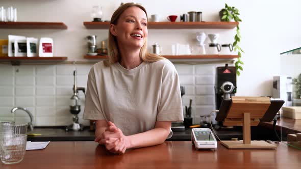 Happy blonde woman barista looking to the side