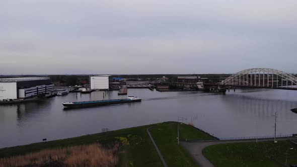 Unloaded Freight Barge Ship Sailing At Noord River With Riverbank Buildings In Netherlands. - Aerial