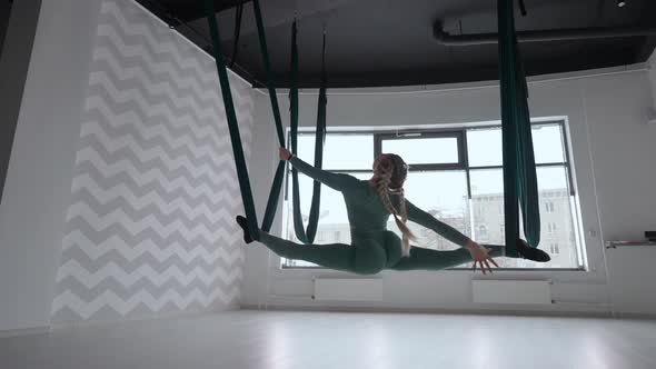 Attractive Fitness Trainer Doing Antigravity Aerial Flying Yoga Exercises in Green Hammock