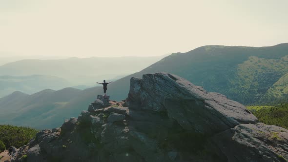 Hiker Stands on a Rock Looking to the Future at Sunset