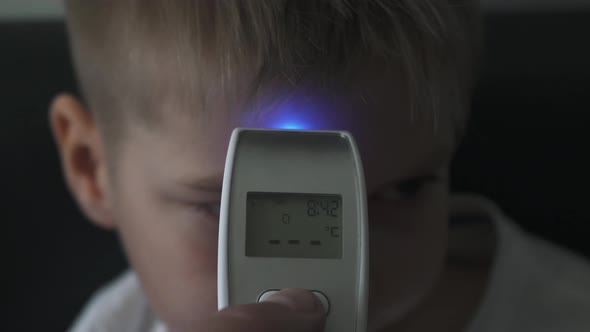 Dad Taking Sons Temperature Using a Digital Thermometer Covid 19 Virus Symptom, display 37.4 Degrees