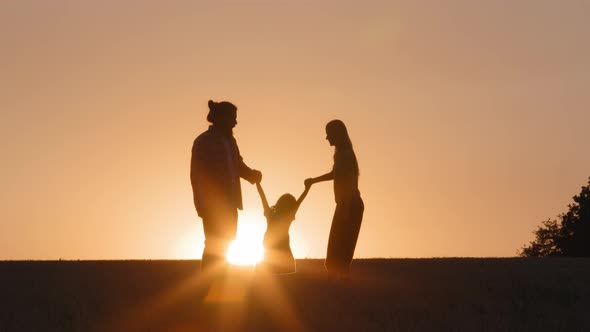 Silhouettes of People at Sunset in Field in Nature in Sun Rays Family Man Women and Child Parents