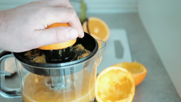 Man Hand View While Squeezing Fresh Orange Fruit on Juicer Healthy Breakfast Preparation Vitamin