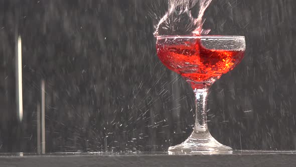 A glass of red wine on a wall in a thunderstorm.