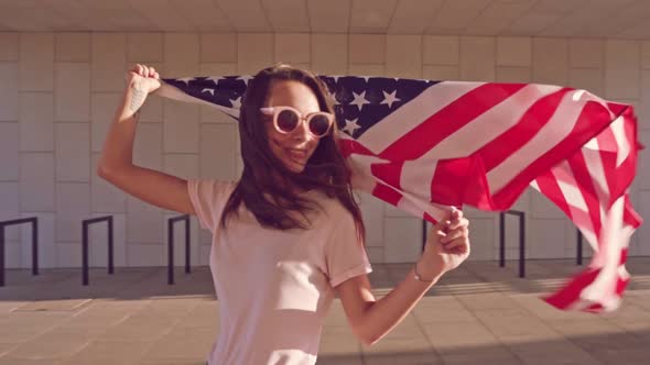 Young Cheerful Caucasian Woman in Sunglasses with Smile Holding Waving USA Flag