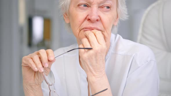 Thoughtful senior businesswoman with grey hair holds glasses