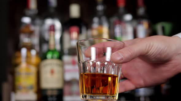 Closeup of a Man Putting a Glass of Whiskey on the Bar