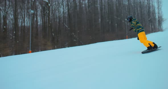 Snowboarder Descends on a Board From a Snowy Slope