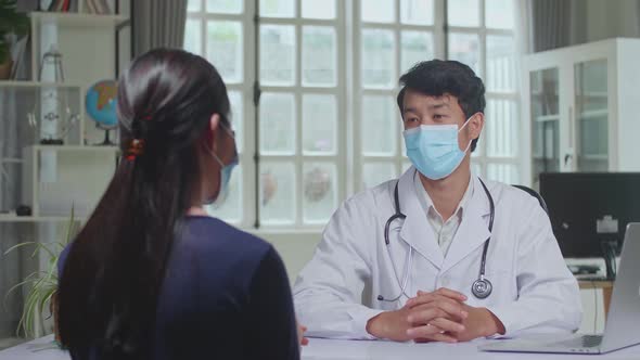 Asian Man Doctor Is Talking With Young Female Patient During Consultation In A Health Clinic