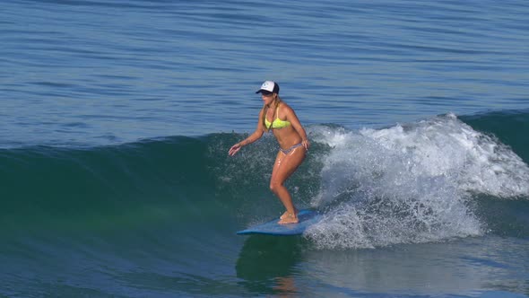 A young woman surfing in a bikini on a longboard surfboard.