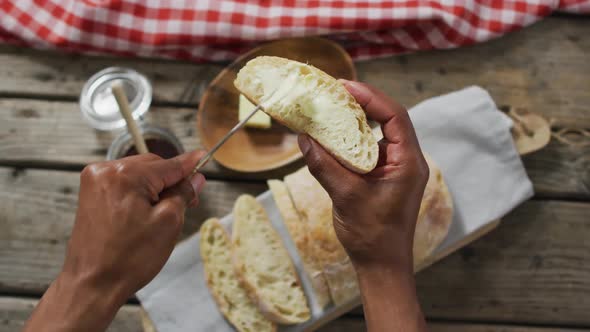 Video of slice of bread in hands on wooden worktop seeing from above