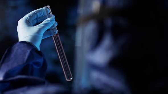 Lab Assistant in Protective Suit Studying Sample in Laboratory Glass Tube Cuvette