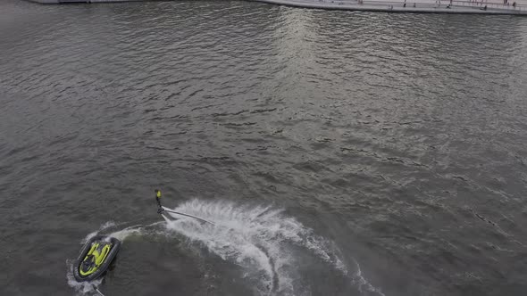 A Man Flies Over the River on a Flyboard and Dives Into the Water