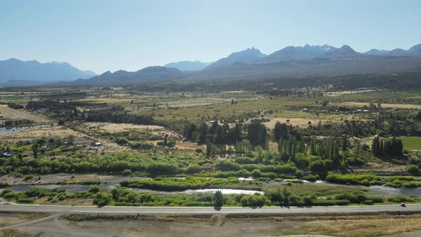 Aerial dolly in flying over Trevelin green valley surrounded by Andean mountains, Patagonia Argentin