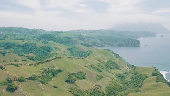 Cinematic aerial drone view of a picturesque landscape of ocean meeting mountains in Batanes, Philip