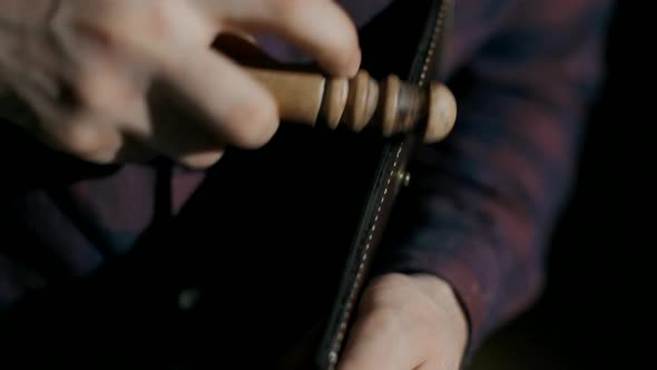 The Process of Manufacturing a Leather Wallet Handmade. The Craftsman Grinds the Finished Product