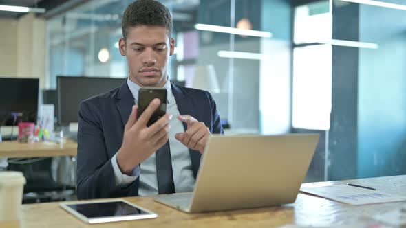 Young African Businessman Using Smartphone in Modern Office