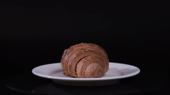 Croissant on white plate rotating in front of camera, Close-up rotates