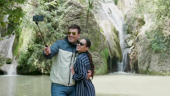 Gorgeous Tourist Couple Takes a Selfie Near a Waterfall