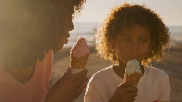 Mother and son eating ice cream with sea in background