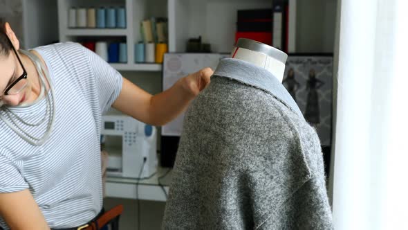 Female designer measuring the length of dress on mannequin 