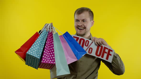 Man Showing Up To 70 Percent Off Inscription and Shopping Bags, Looking Satisfied with Low Prices