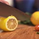 Woman's Hands Cutting Fresh Lemon on Wooden Cutting Board Using Kitchen Knife - VideoHive Item for Sale