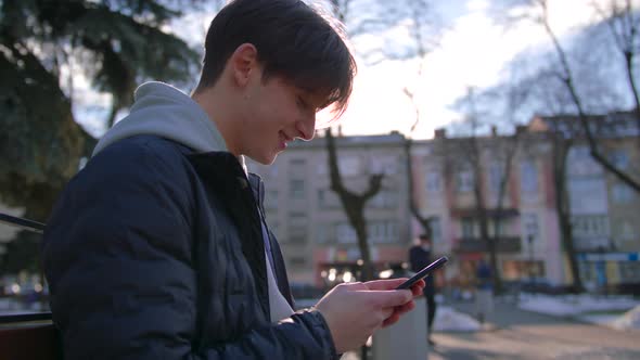 Young Man Texting on Cell Phone Looking Around