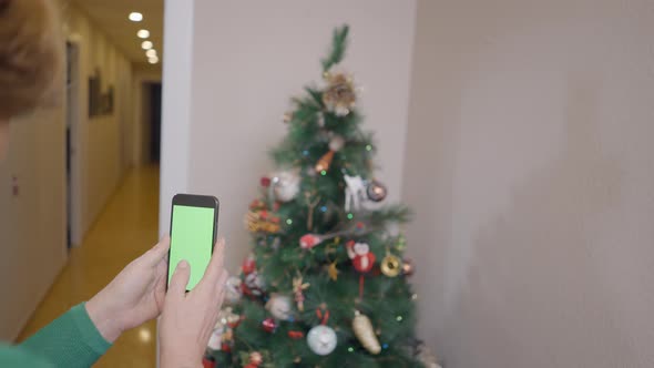 Woman In The House Taking Photo Of Decorative Christmas Tree With Smartphone Camera