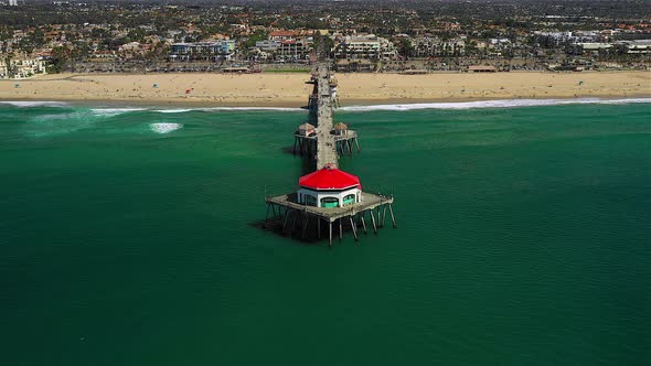 Drone footage of the Huntington Beach pier. Pans from the ocean, pier, beach, and city