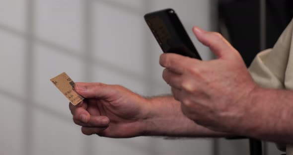 Adult Male makes a credit card purchase over his cellphone straight on shot