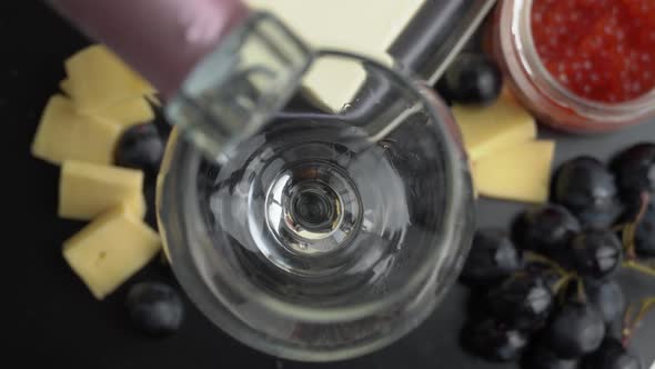 Rose Wine is Poured Into a Glass With Snacks