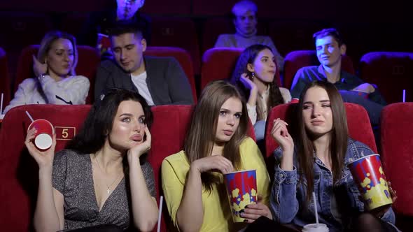 Three Frustrated Young Girls Watching an Uninteresting Movie at the Cinema.