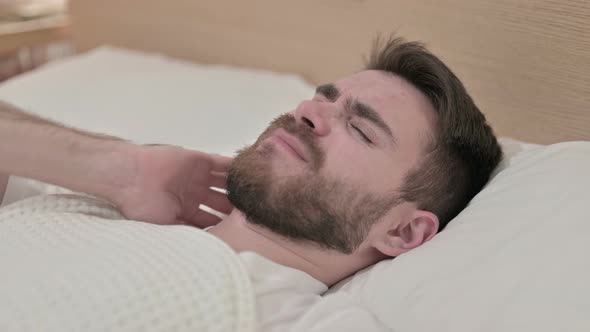 Sleeping Young Man Having Neck Pain in Bed 